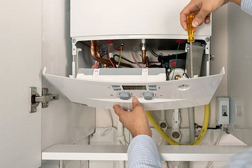 Heating technician repairing a residential boiler in West Sacramento