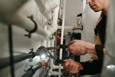 Technician inspecting commercial plumbing pipes in West Sacramento