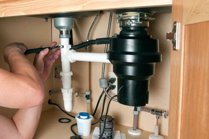 Plumber repairing a garbage disposal in West Sacramento