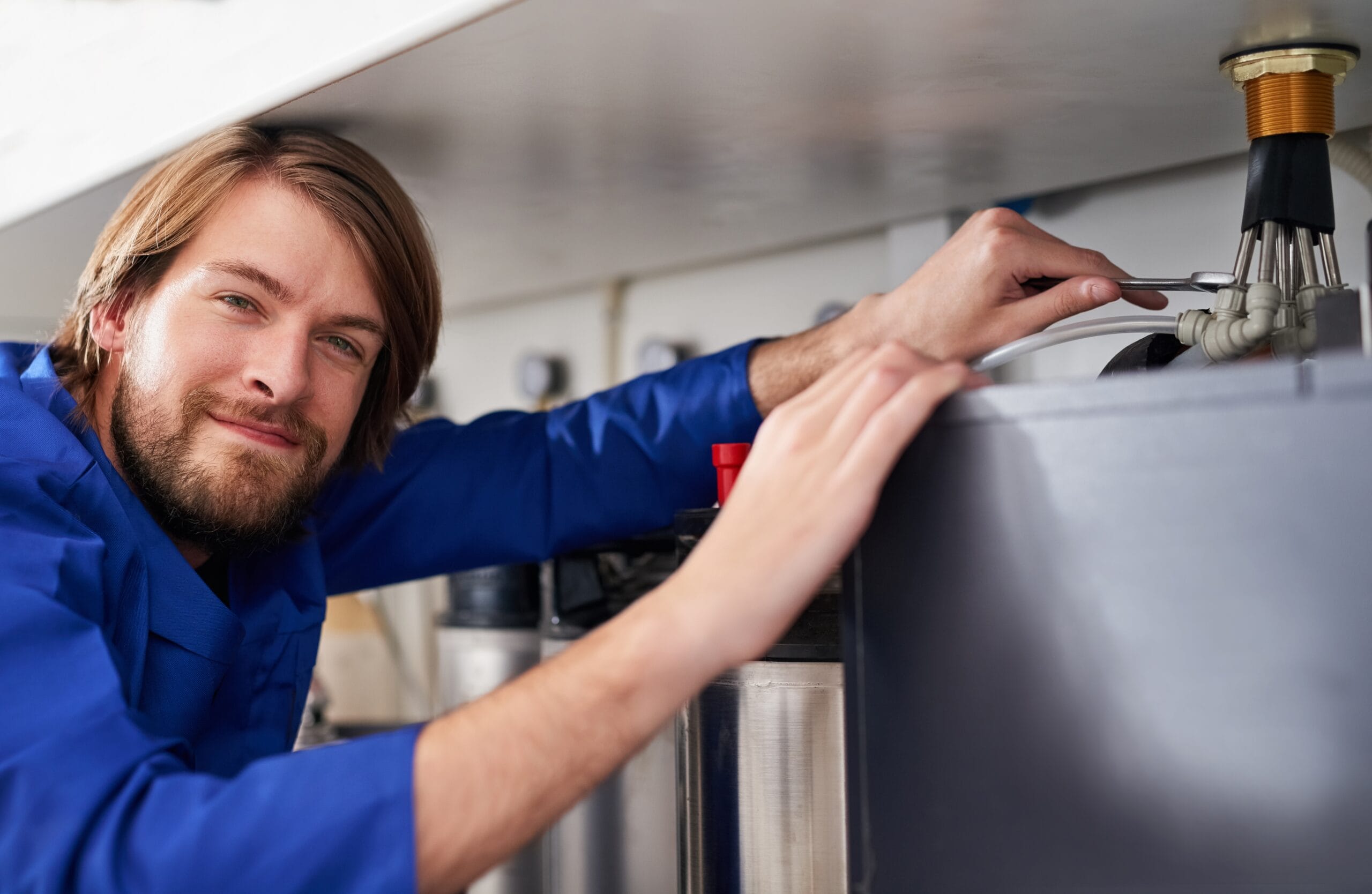 Technician servicing a residential water heater tank in West Sacramento